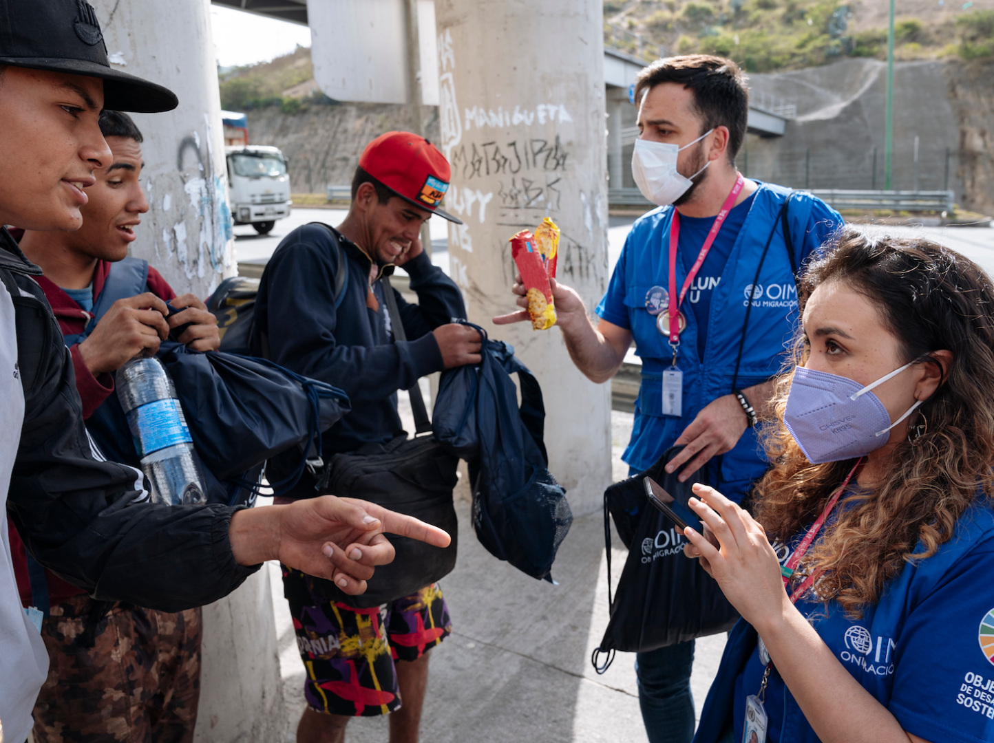 Voluntarios/as ONU de OIM entregando kits de dignidad a personas en tránsito.