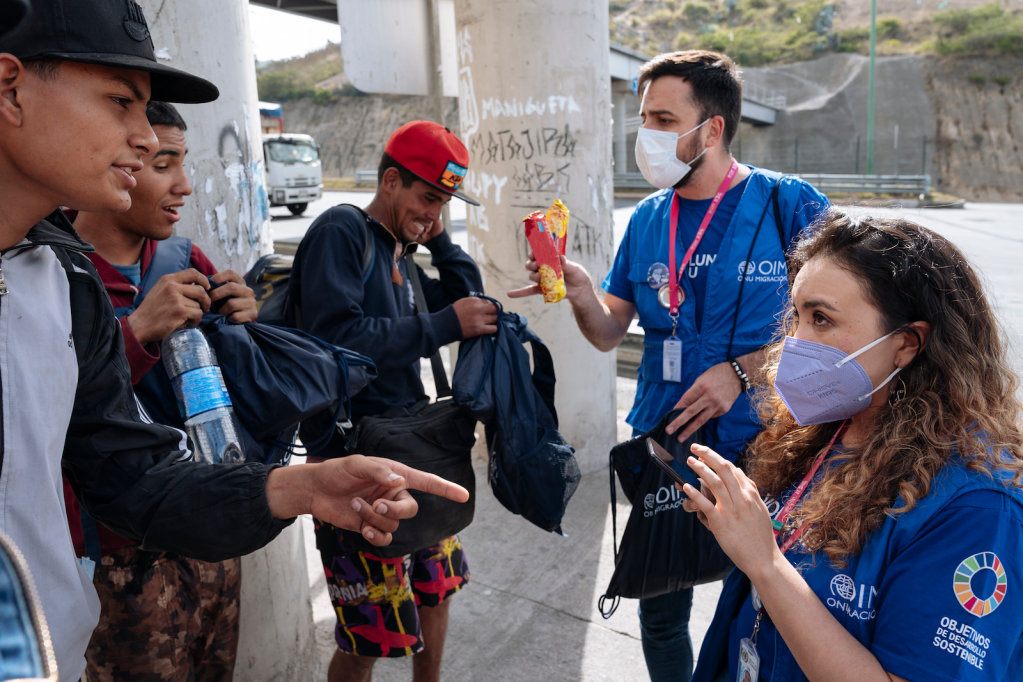 Voluntarios/as ONU de OIM entregando kits de dignidad a personas en tránsito.