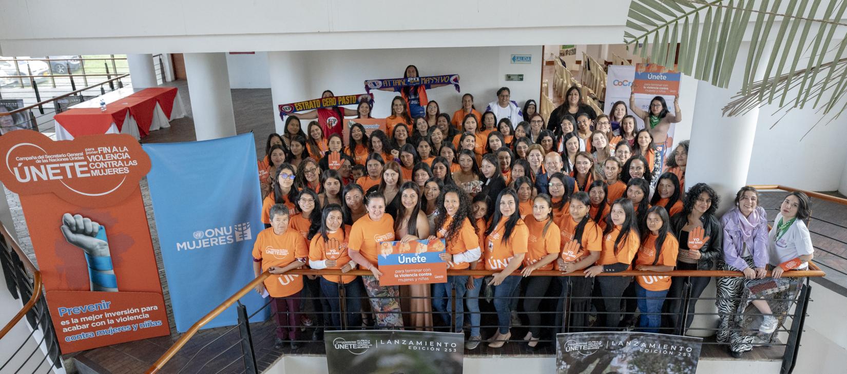 Grupo de mujeres vistiendo de naranja con avisos y pendones de Únete para poner fin a la violencia de género.