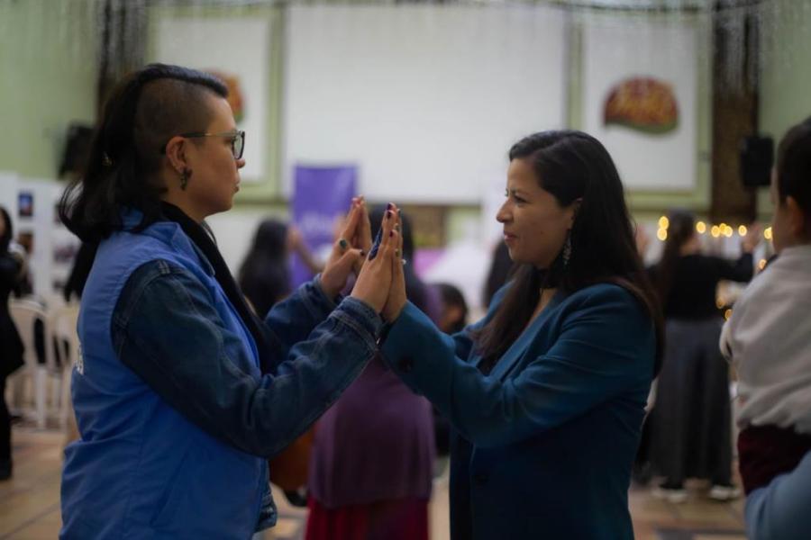 Dos mujeres una frente a la otra conectándose con las palmas de sus manos