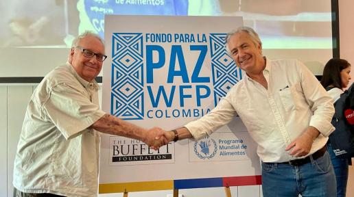 El filántropo estadounidense Howard Buffet (izquierda) y Carlo Scaramella, Director de País de WFP Colombia (derecha) estrechan la mano delante de un cartel que dice Fondo para la Paz WFP Colombia.